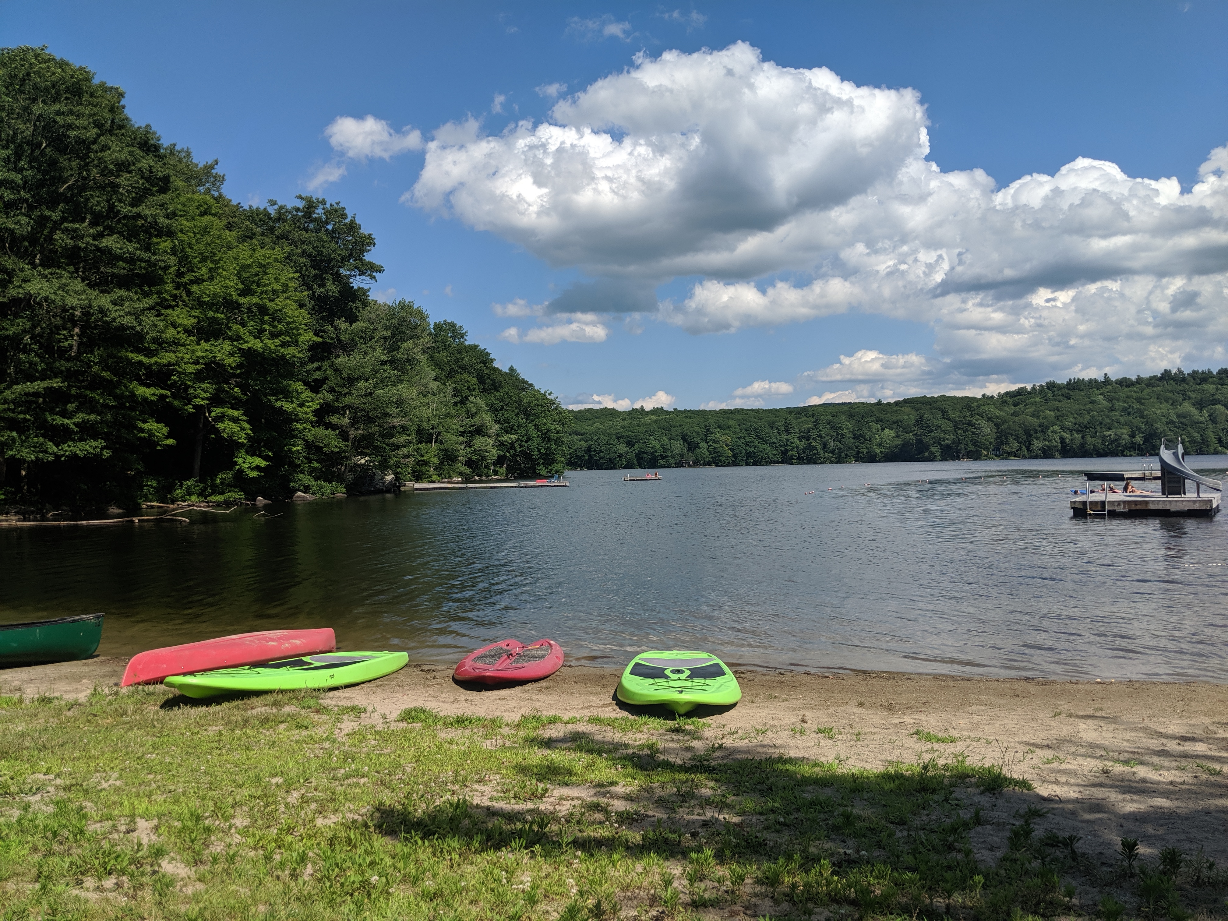 Paddleboards and canoes on the beach at Cream Hill Lake on a sunny summer day